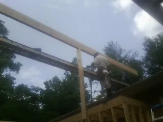 Carpenter setting a ridge beam over a new addition frame — Ice Dam Removal by Roofing Brothers in Evans Mills
