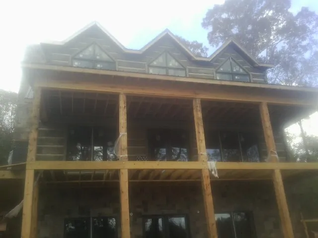 Dormers and porch framing on a large log home under construction — Roof Coating work by our crew in Evans Mills