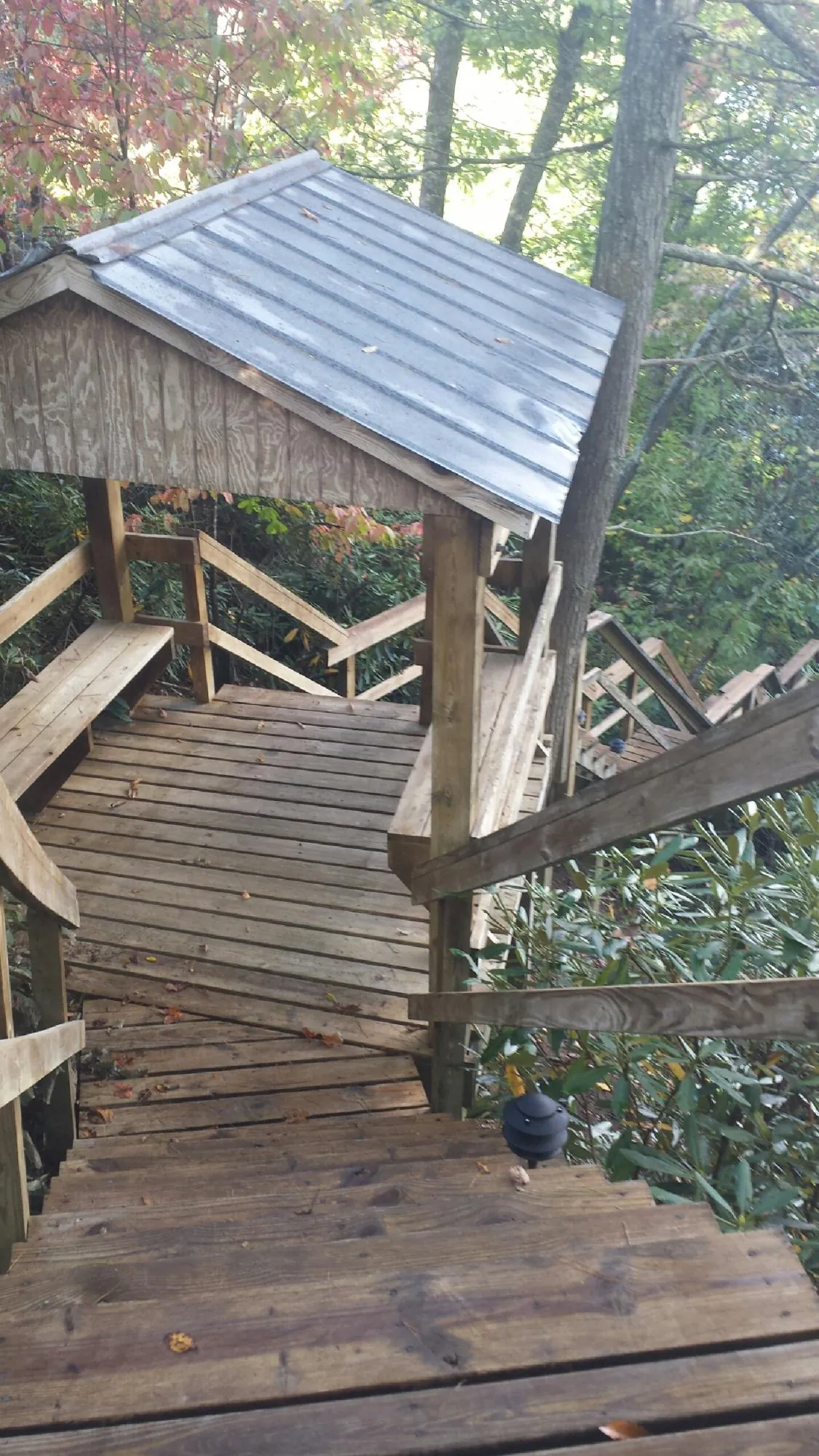 Metal roofed shelter over wooden steps on a wooded walkway — Skylight Repair & Installation work by our crew in Evans Mills