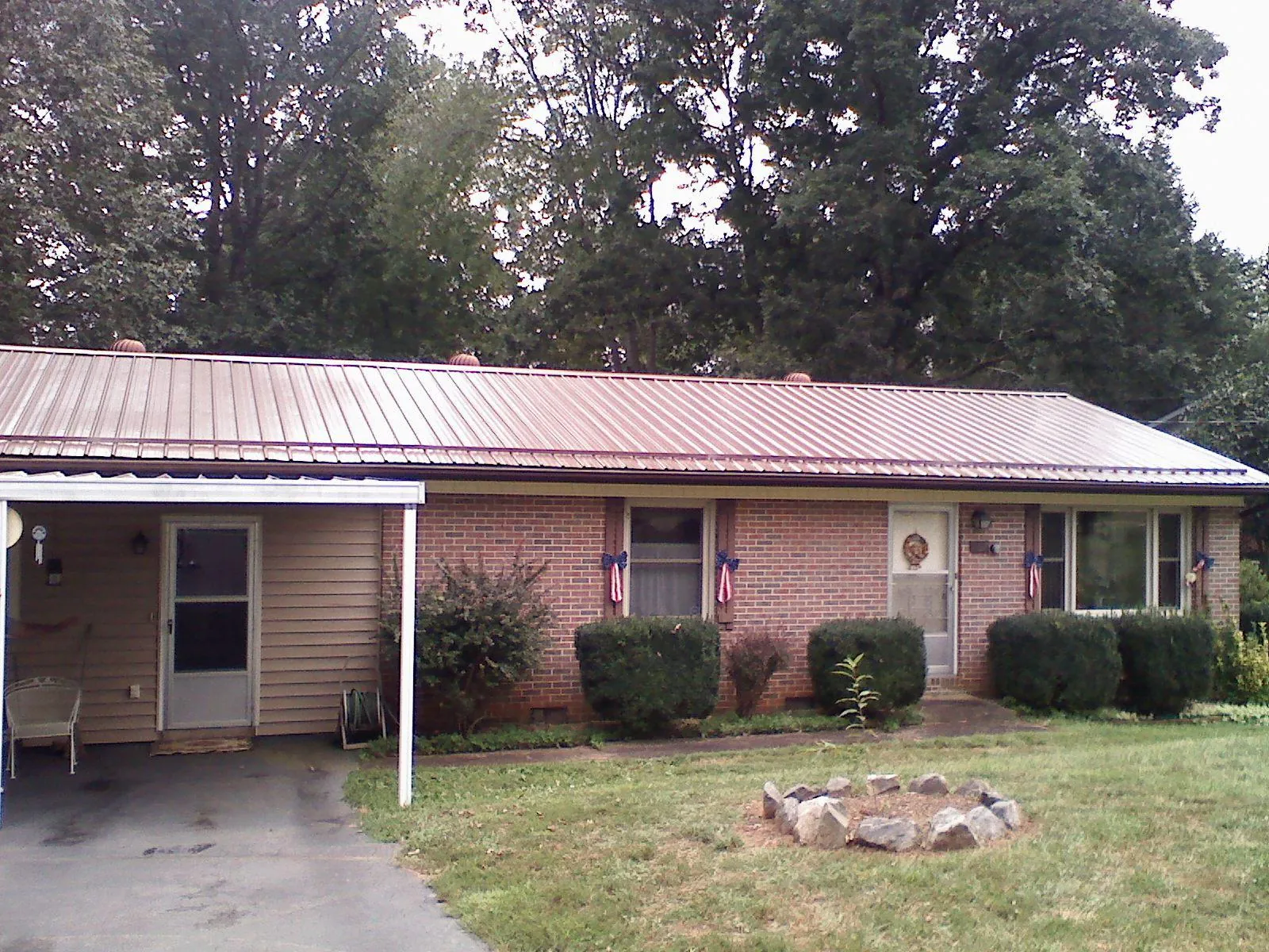 Bronze metal roof and carport on a brick ranch home — Roof Repair work by our crew in Evans Mills